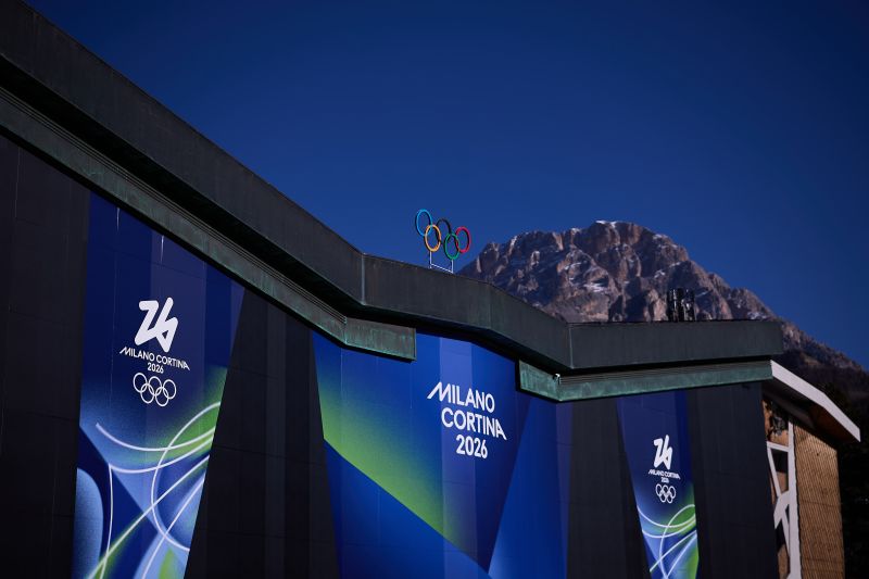 Milano Cortina 2026 — branded building with Olympic rings and mountain backdrop